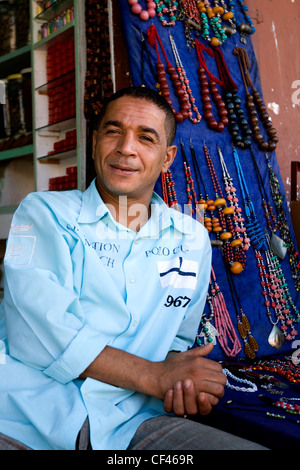 Eine lokale Kostüm Schmuck Verkäufer sitzt vor seinem Geschäft warten auf Kunden, Djemaa el-Fna Markt in Marrakesch Marokko Stockfoto