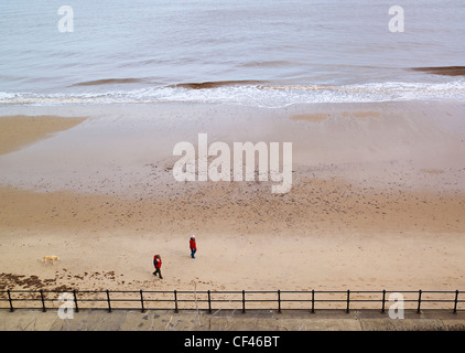 Ein paar am Strand von Mundesley mit ihrem Hund spazieren. Stockfoto