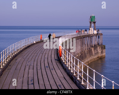 Menschen zu Fuß auf Whitby West Pier Ausdehnung an einem sonnigen Frühlingstag Stockfoto