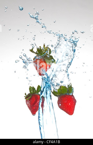 drei Erdbeeren werden mit Wasser bespritzt Stockfoto