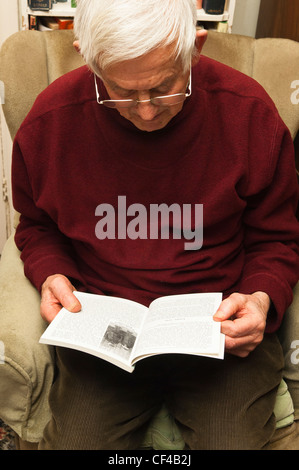 Ein senior ältere Mann in seinem 80 Lesung des ein Buch zu Hause in England, Großbritannien, Vereinigtes Königreich Stockfoto