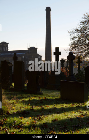 Der Friedhof von The Holy Trinity Church, Queensbury, West Yorkshire, mit Turm von Black Dyke Mühle im Hintergrund. Stockfoto