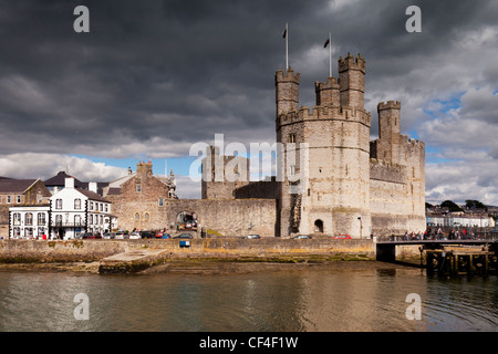 Caernarfon Castle, die Anglesey Pub und der Fluss-Seiont unter einem spektakulären dunklen Himmel. Stockfoto