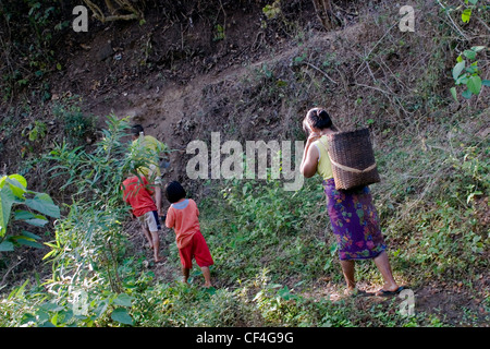 Frau Karen Flüchtlinge aus Burma spaziert im Nationalpark Salawin mit ihren Kindern in der Nähe von Ban Tha Ta Fang, Nord-Thailand. Stockfoto