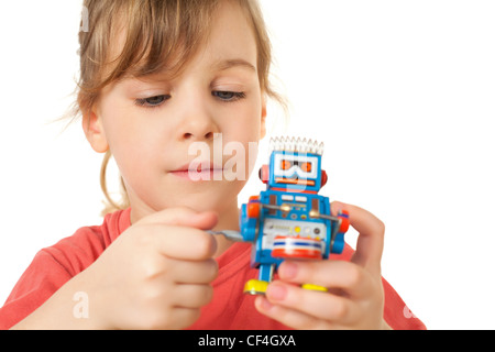 hübsches kleines Mädchen im roten T-shirt spielt mit Clockwork Roboter isoliert auf weißem Hintergrund Stockfoto