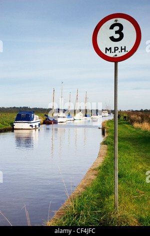 A 3 mh Höchstgeschwindigkeit Zeichen auf den Norfolk Broads mit Yachten vor Anker im Hintergrund. Stockfoto