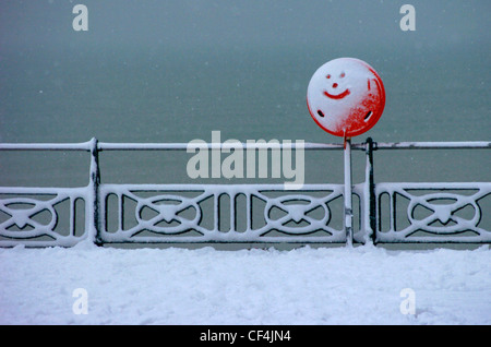 Ein Smiley-Gesicht in den Schnee bedeckt ein rotes Schild am Strand von Brighton gezeichnet. Stockfoto