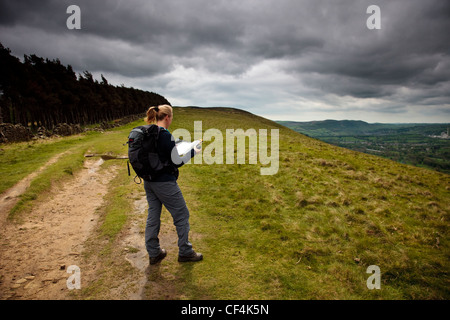 Eine junge Frau anhalten um zu überprüfen, ihre Karte auf einen Spaziergang in den Hügeln der Peak District National Park. Stockfoto