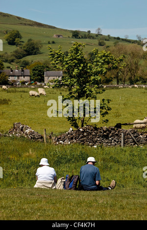 Ein paar Wanderer sitzen in einem Feld eine Pause an einem sonnigen Tag im Peak District National Park. Stockfoto