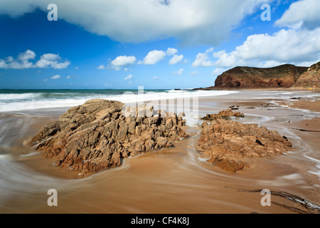 Wirbelnden Flut um Felsen am sandigen Strand von Plemont Bay in Jersey. Stockfoto