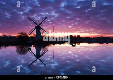 Thurne Deich Entwässerung Mühle spiegelt sich in den Fluß Thurne bei Sonnenaufgang auf den Norfolk Broads. Stockfoto