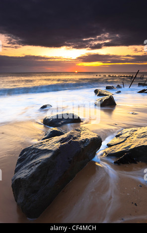 Die Flut wirbelt um die Felsen der Happisburghs Meer Verteidigung. Stockfoto