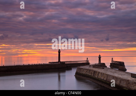 Sonnenuntergang über den Westen und Osten Piers in Whitby an einem Sommerabend. Stockfoto