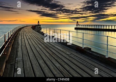 Sonnenaufgang über den Westen und Osten Piers in Whitby. Stockfoto