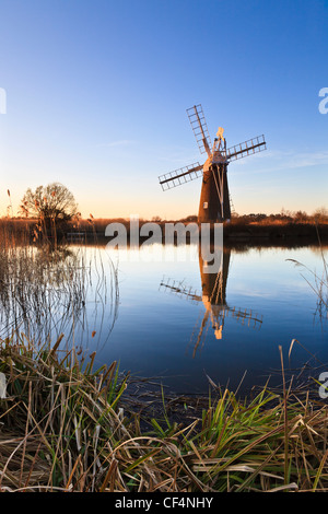 Turf Moor Wind Pumpe spiegelt sich in stilles Wasser wie Hill an einem Winter-Abend. Stockfoto