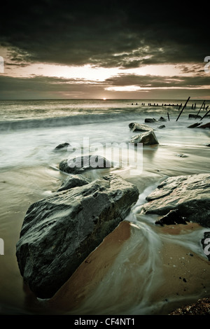 Die Flut wirbeln um den Felsen des Happisburghs Meer Verteidigung. Stockfoto