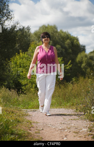 Frau im sonnigen Tag auf Holz Lichtung geht am Weg in Sonnenbrillen Stockfoto