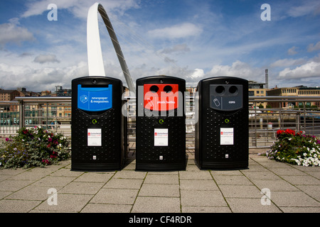 Recycling-Behälter am Kai in Gateshead mit die Gateshead Millennium Bridge im Hintergrund. Stockfoto