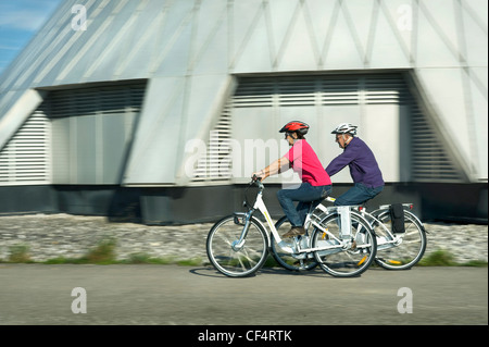 Deutschland, Bayern, Raisting, Senior paar Reiten Elektro-Fahrrad in der Nähe von Radiosender Stockfoto