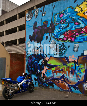 Ein Motorrad geparkt vor einer Wand in Graffiti bedeckt. Stockfoto