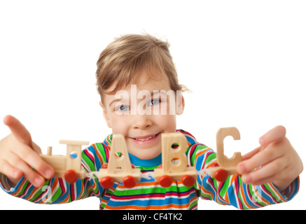 hübsches kleines Mädchen hält in Händen Spielzeug aus Holz Dampflok mit Autos in Form von Buchstaben, die isoliert auf weißem Hintergrund Stockfoto