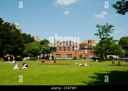 Menschen entspannen im Klostergarten mit Abbey House in der Ferne. Stockfoto