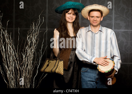 junge schöne Frau und lächelnder Mann in Sombrero und mit Trommel Stockfoto