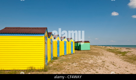 Leuchtend gelben und grünen Strandhütten am Strand von Littlehampton. Stockfoto