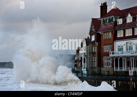 Rauen Nordsee erstellen einen spektakulären Anblick als Wellen brechen gegen die Strandpromenade Whitbys. Stockfoto