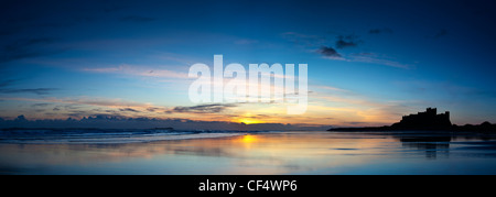 Blick über den Strand bei Sonnenaufgang in Richtung Bamburgh Castle, ehemaligen Hause zu Kings of Northumbria. Stockfoto