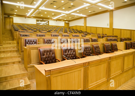 Konferenzräume mit herrlichen Ledersesseln und Holztische mit Mikrofonen, Verkürzungen seitwärts Stockfoto