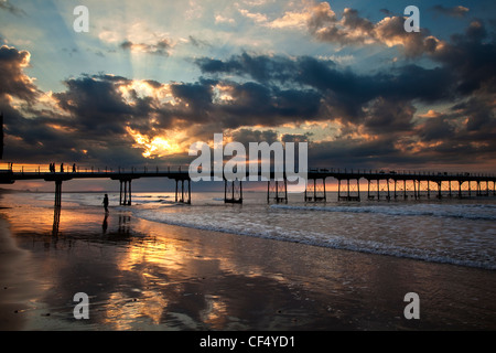 Sonnenstrahlen von der untergehenden Sonne über den viktorianischen Pier in Saltburn-By-The-Sea. Stockfoto