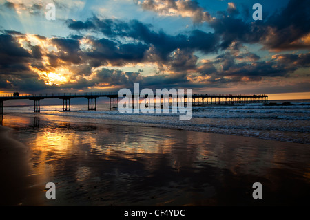 Sonnenstrahlen von der untergehenden Sonne über den viktorianischen Pier in Saltburn-By-The-Sea. Stockfoto