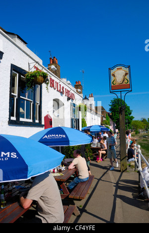 Menschen sitzen vor The Bulls Head Pub am Strand-on-the-Green Nordufer der Themse. Stockfoto