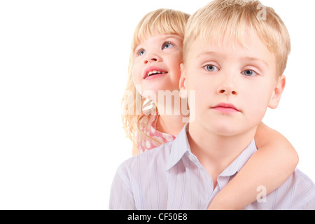 kleine Mädchen und Traurigkeit kleiner Junge. Schwester umarmt Bruder. isoliert. Stockfoto