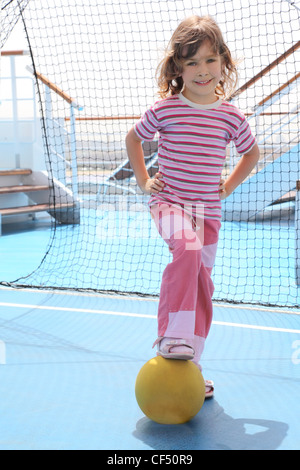 kleines Mädchen mit gelben Ball Stand in der Nähe Fußballtor auf Cruise Liner Deck Sommertag Stockfoto