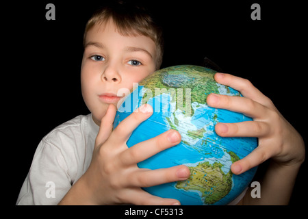 junge umarmen Globus der Welt auf schwarzem Hintergrund isoliert Stockfoto