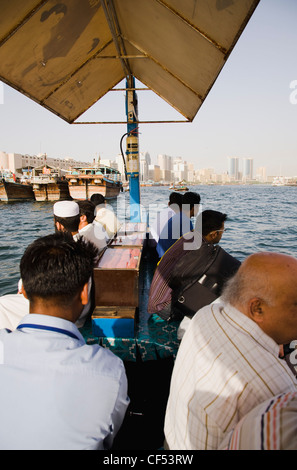 Vereinigte Arabische Emirate, Golfstaat, Dubai, Abra Wasser taxis mit Passagieren auf dem Creek mit Twin Towers und die Skyline hinter vorbei. Stockfoto