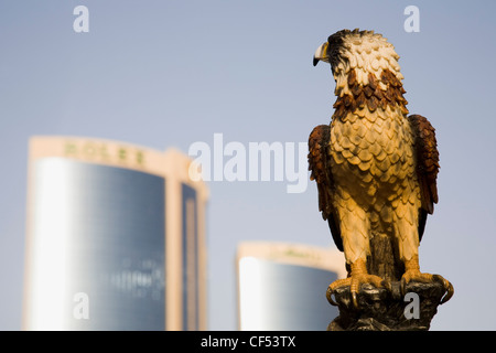 Vereinigte Arabische Emirate, Golfstaat, Dubai, Falcon-Statue auf dem Creek mit Twin Towers Einkaufszentrum hinter. Stockfoto