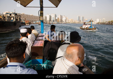 Vereinigte Arabische Emirate, Golfstaat, Dubai, Abra Wasser taxis mit Passagieren auf dem Creek mit Twin Towers und die Skyline hinter vorbei. Stockfoto