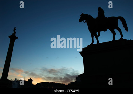 Statue von König George IV auf dem Pferderücken und Nelsons Säule in der Silhouette. Stockfoto