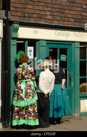 Drei Frauen in Dickens Kostüm in eine Bäckerei an der Rochester High Street während Dickens Festival suchen. Stockfoto