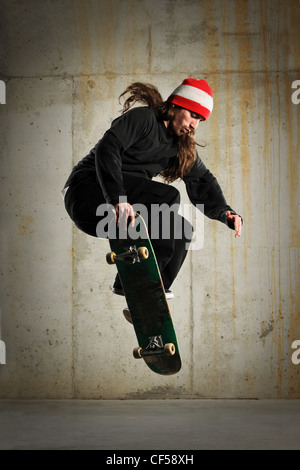 Skateboarder Kunststücke mit Grunge Wand als Hintergrund Stockfoto
