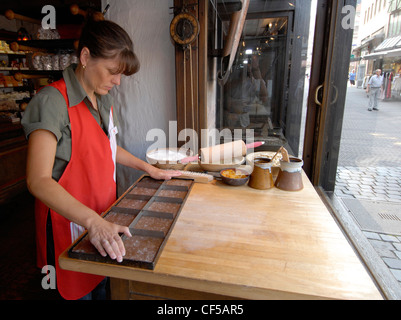 Ein Bäcker schneidet Lebkuchen in Quadrate, bevor er in der Bäckerei Lebkuchen Schmidt auf dem Hauptmarkt (Nürnbergs Hauptplatz) in Deutschland bäckt. Stockfoto