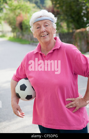 Deutschland, Bayern, Huglfing, Senior Frau mit Fußball, Lächeln, Porträt Stockfoto