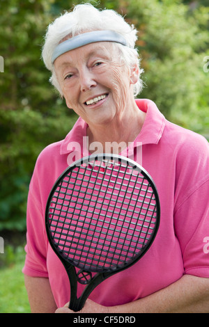 Deutschland, Bayern, Huglfing, Senior Frau hält Federballschläger, Lächeln, Porträt Stockfoto