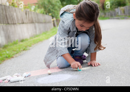 Deutschland, Bayern, Huglfing, Mädchen auf der Straße mit Kreide zeichnen Stockfoto