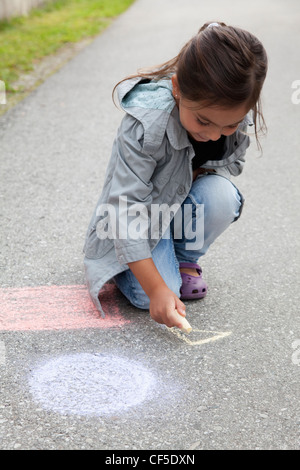 Deutschland, Bayern, Huglfing, Mädchen auf der Straße mit Kreide zeichnen Stockfoto