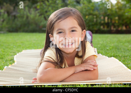 Deutschland, Bayern, Huglfing, Mädchen liegen im Garten, Lächeln, Porträt Stockfoto