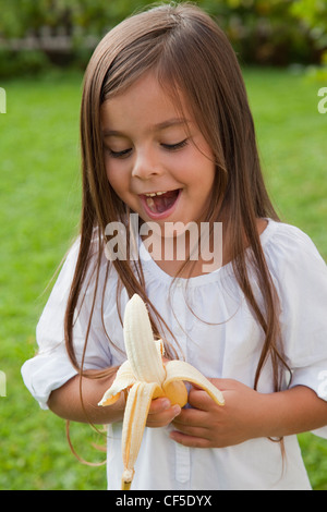 Deutschland, Bayern, Huglfing, Mädchen mit Banane im Garten, Lächeln Stockfoto